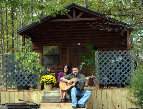 Bunny and Arvie Bennett sitting on a porch outside their tiny cabin.